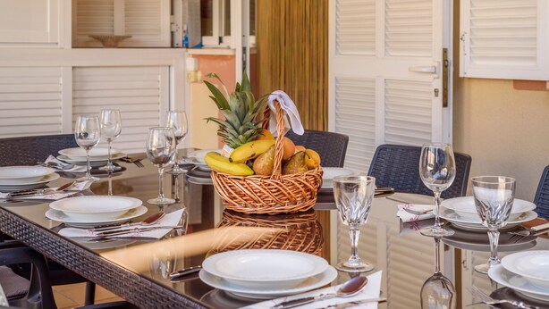 A dining table set with plates, cutlery, and a fruit basket.