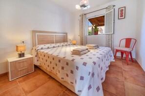 Camera da letto con un letto, comodino, lampada, sedia, finestra e tende.
