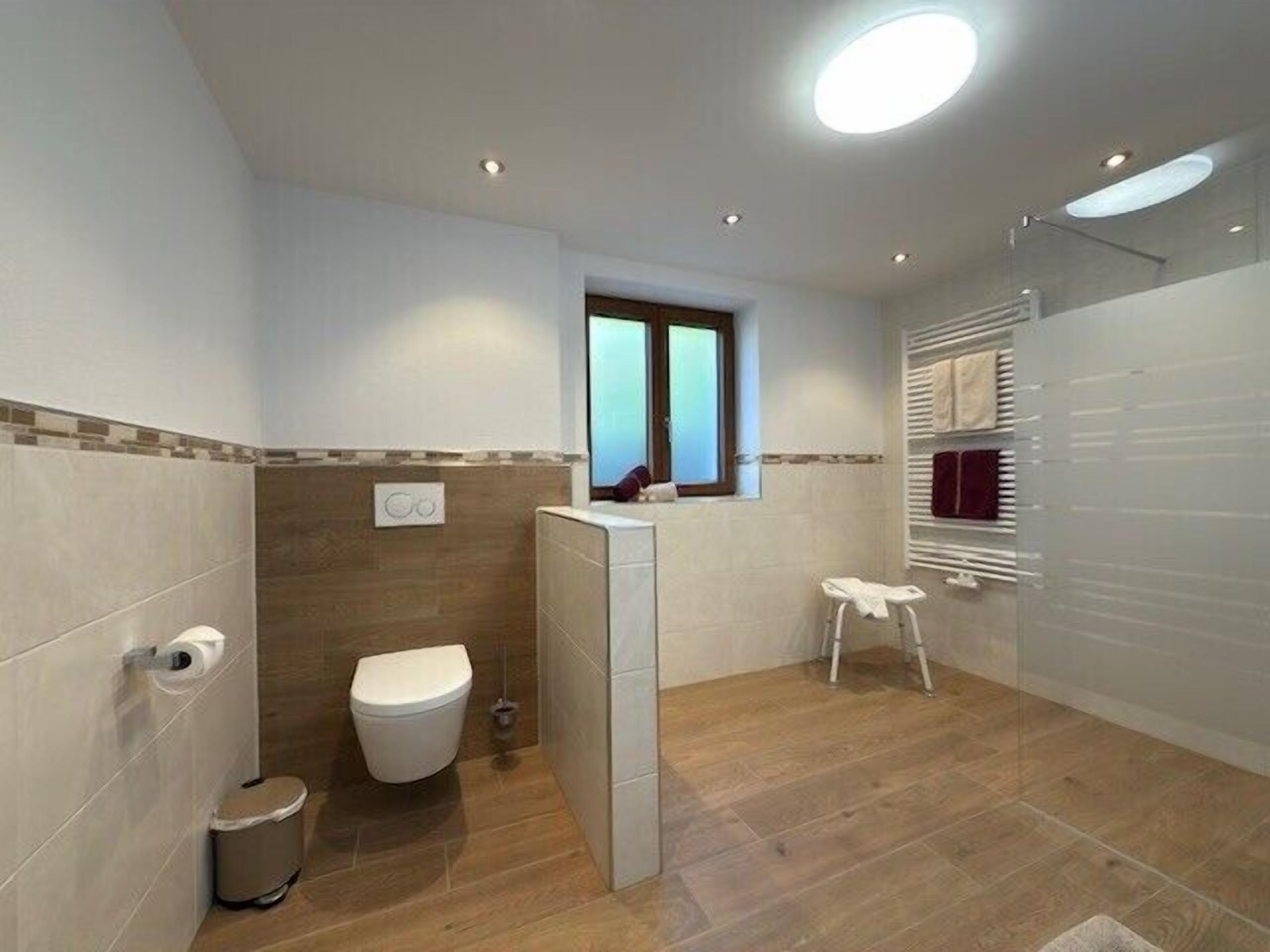 A modern bathroom with a toilet, bidet, and a small stool.