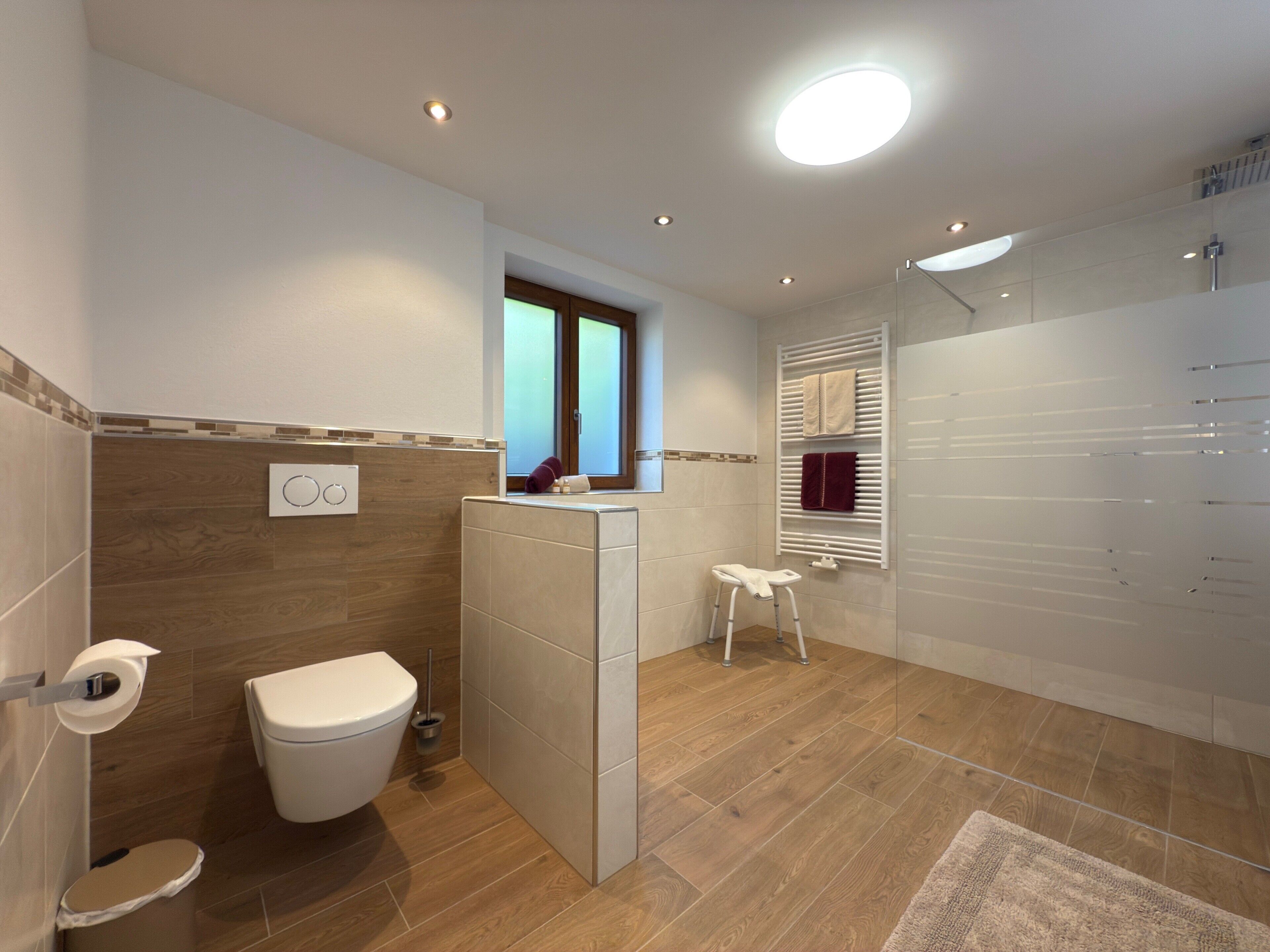 A modern bathroom with a toilet, bidet, vanity, and a shower area.