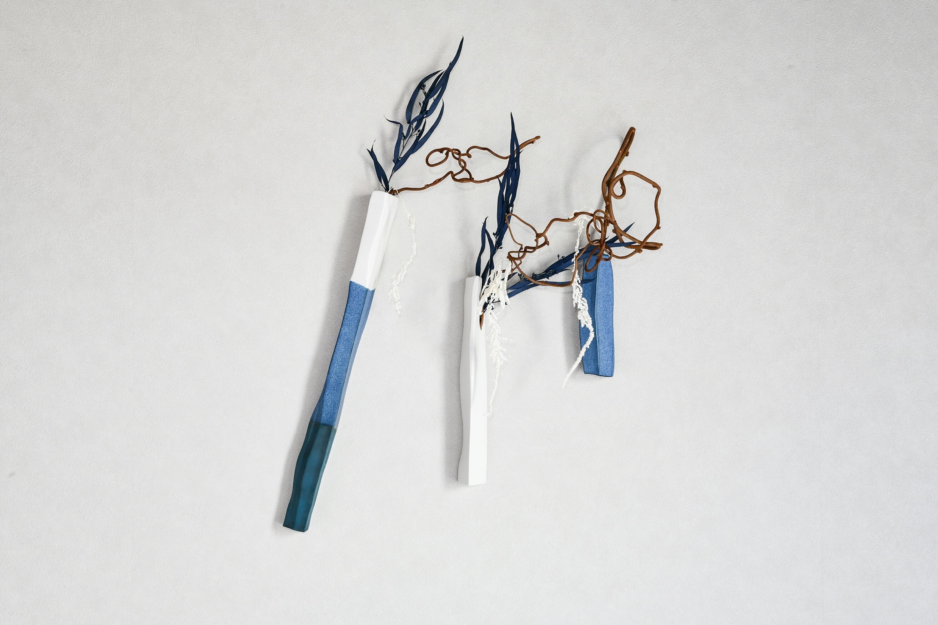 Three abstract sculptures with blue and white elements on a plain background.