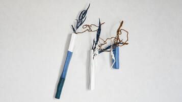 Three abstract sculptures with blue and white elements on a plain background.