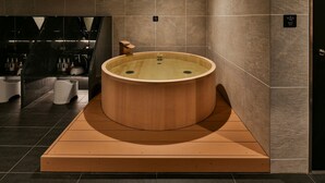 Uma área de spa moderna com uma banheira de hidromassagem de madeira, um aviso de sauna e uma área de pia visível.