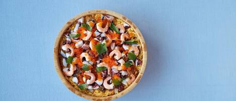 A wooden bowl filled with seafood salad on a blue background.