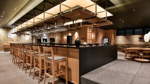 Uma área de bar moderna com um balcão comprido, vários bancos e uma variedade de copos.