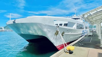 A white boat docked at a pier with the name "SHOKU" visible on its side.