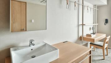 Casa de banho moderna com toucador de madeira, lavatório branco e espelho.