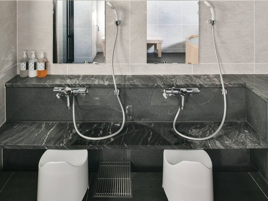 Un baño moderno con dos lavamanos, un espejo y zona de ducha.