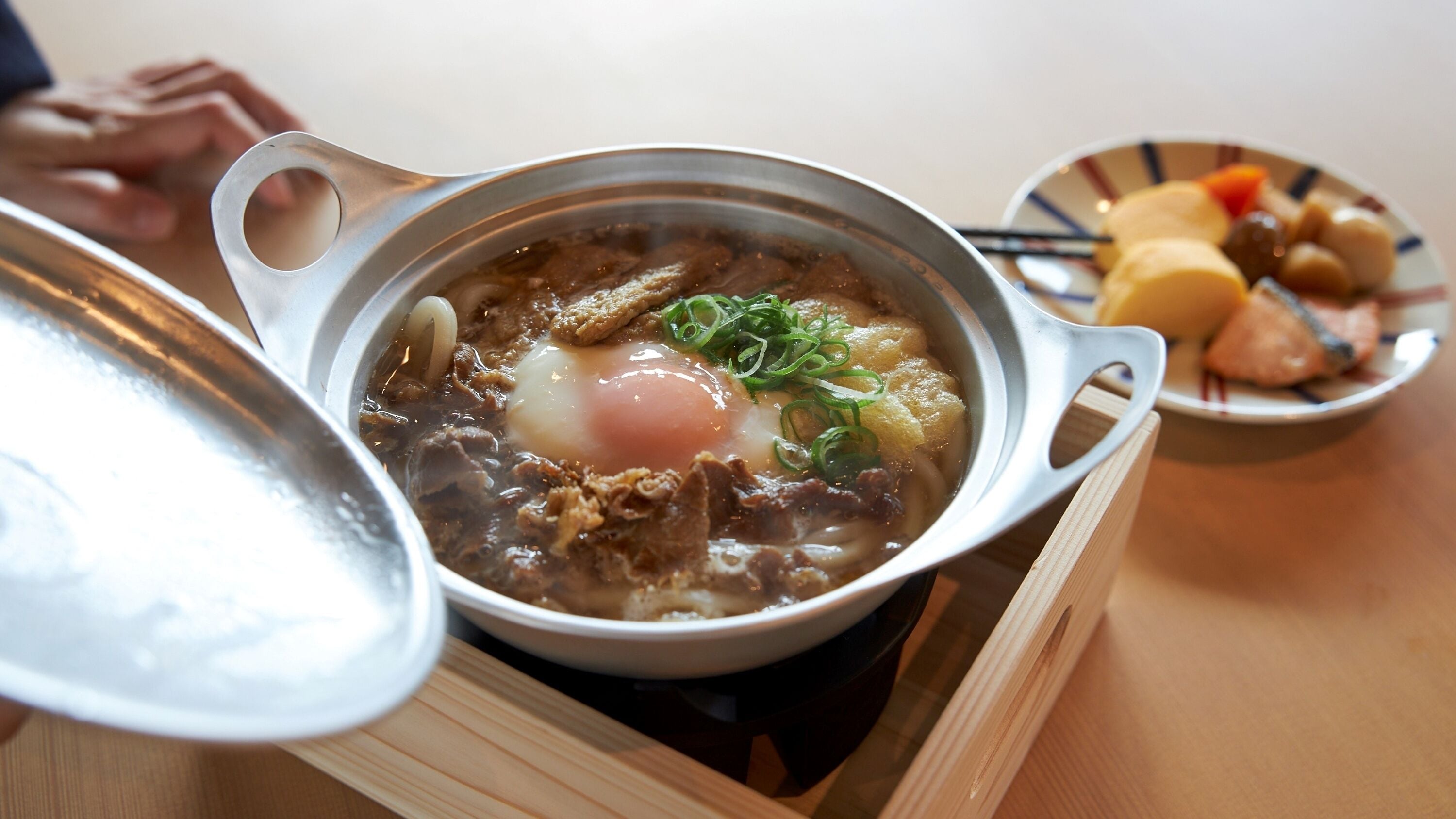 A hot pot with meat and vegetables, a bowl of dumplings, and a plate of assorted items.