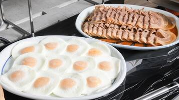 A table with two dishes: one plate of sliced meat and one plate of fried eggs.