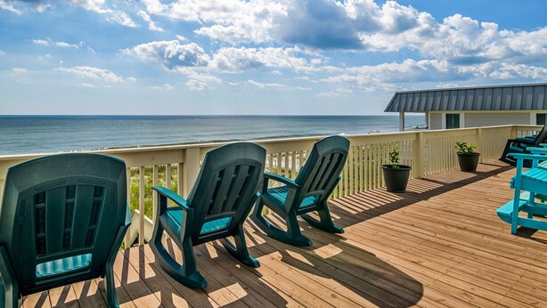 A wooden deck with chairs and potted plants, overlooking the ocean. - "Sandpiper Crossing" - Luxury Oceanfront Home, 4 Bedrooms / 3.5 Bathrooms (Holden Beach)