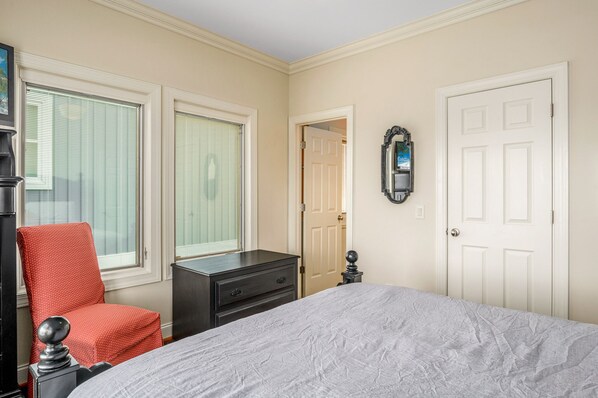 Une chambre à coucher avec un lit, une commode, une chaise et une porte.
