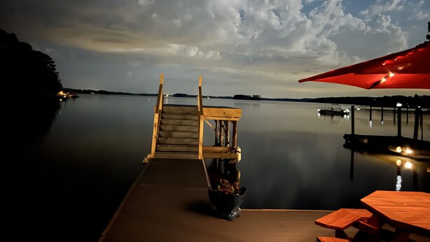 A wooden dock extending into calm water with a wooden bench and a table with an umbrella. - Million Dollar Sunrise View (Batesburg-Leesville)