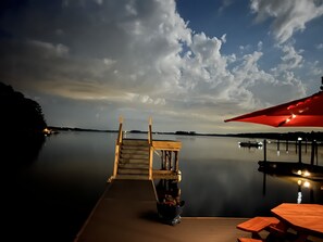 A wooden dock extending into calm water with a wooden bench and a table with an umbrella. - Million Dollar Sunrise View (Batesburg-Leesville)