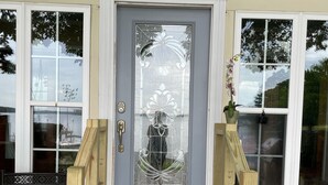 A front porch with a wooden staircase leading to a grey door with a decorative glass panel. - Million Dollar Sunrise View (Batesburg-Leesville)