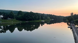 A calm river with a bridge on the right and a boat in the middle.