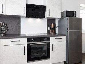 Eine moderne Küche mit Edelstahlgeräten, darunter ein Backofen, eine Mikrowelle und ein Kühlschrank.
