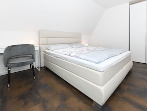 A bedroom with a bed, a chair, and a desk.