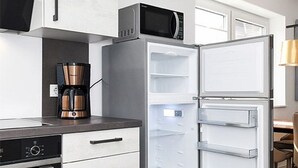 Eine moderne Küche mit integriertem Mikrowellenherd, einer Kaffeemaschine und einem Kühlschrank mit mehreren Ablagen.