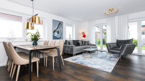Ein modernes Wohnzimmer mit Essbereich, ausgestattet mit einer Sofagarnitur, einem Couchtisch und einem Esstisch mit Stühlen.