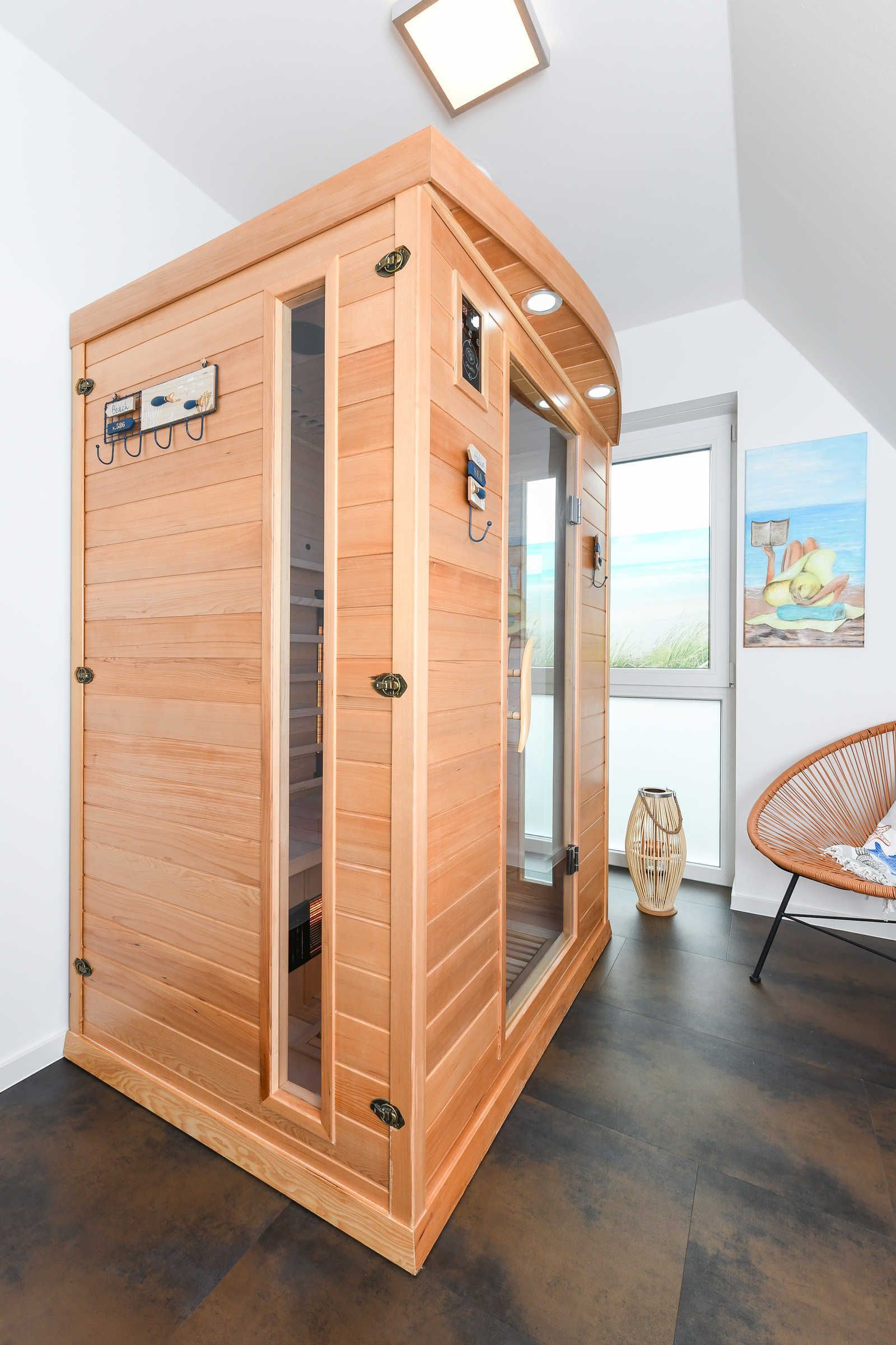Una sauna con revestimiento de madera, puerta de cristal y panel de control en la pared.