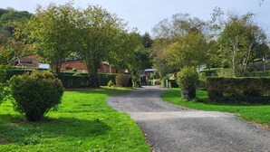 A gravel path leading through a green landscape with neatly trimmed hedges and trees. - Mobilhome Betzula 3ch (Larrau)