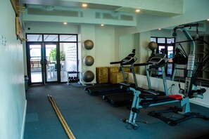 Un gimnasio con cintas de correr, una banca para pesas y pelotas de ejercicio.