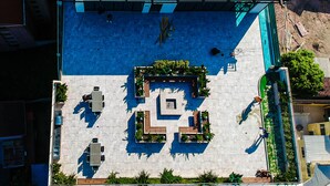 Vista aérea de un edificio moderno con jardín en la azotea, un patrón geométrico de macetas y un amplio ventanal con estructura metálica.