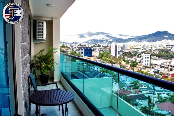 Un balcón con vistas a un paisaje urbano y montañas.