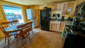 Una cabaña de madera con comedor, cocina y vistas al exterior.