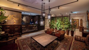 A hotel lobby with a reception desk, seating area, and decorative plants. - Tbilisee Hotel (Tbilisi)