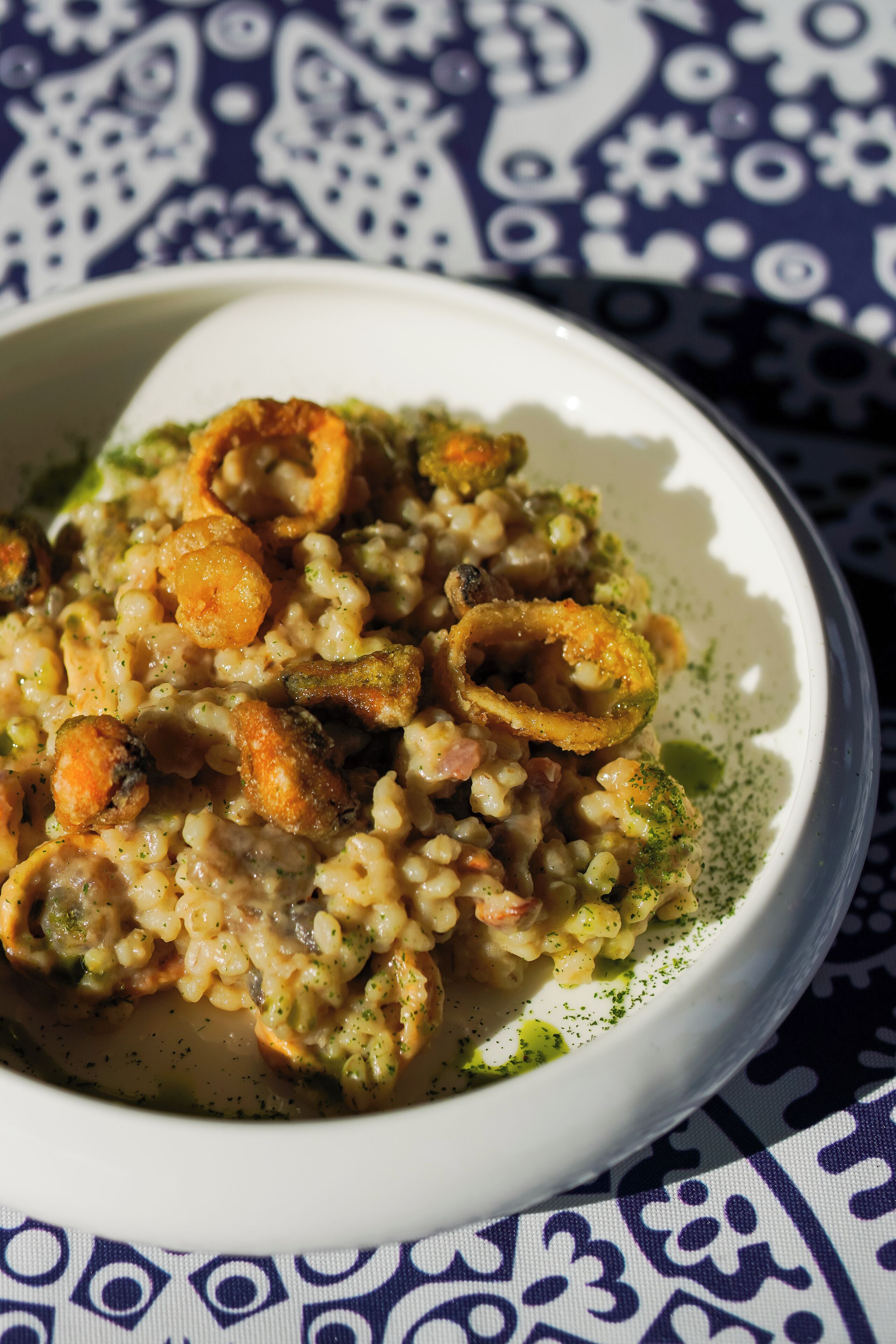 Un plato de comida con arroz, camarones y aros de cebolla.