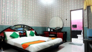 Een hotelkamer met een bed, een dressoir, een spiegel en uitzicht op een roze gebouw.