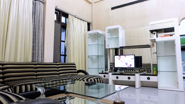 Een moderne woonkamer met een bank, een glazen salontafel en een flatscreen televisie.
