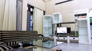 Een moderne woonkamer met een bank, een glazen salontafel en een flatscreen televisie.