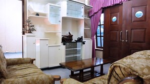 A living room with a sofa, a coffee table, and a wooden cabinet with glass doors.