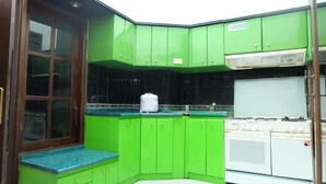 Een keuken met groene kasten, een witte kookplaat en een blauw aanrecht.
