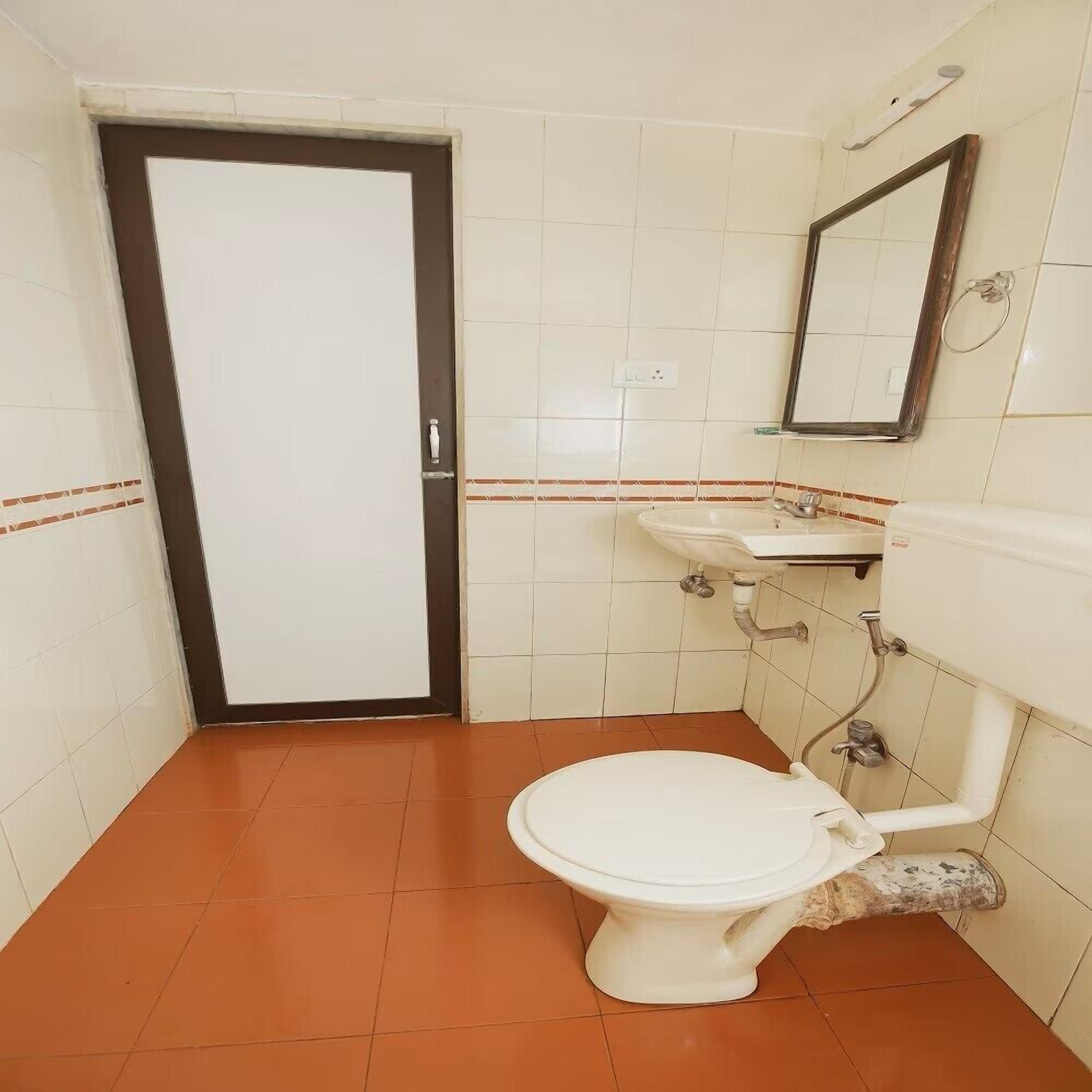 A bathroom with a white toilet, a sink, and a mirror.
