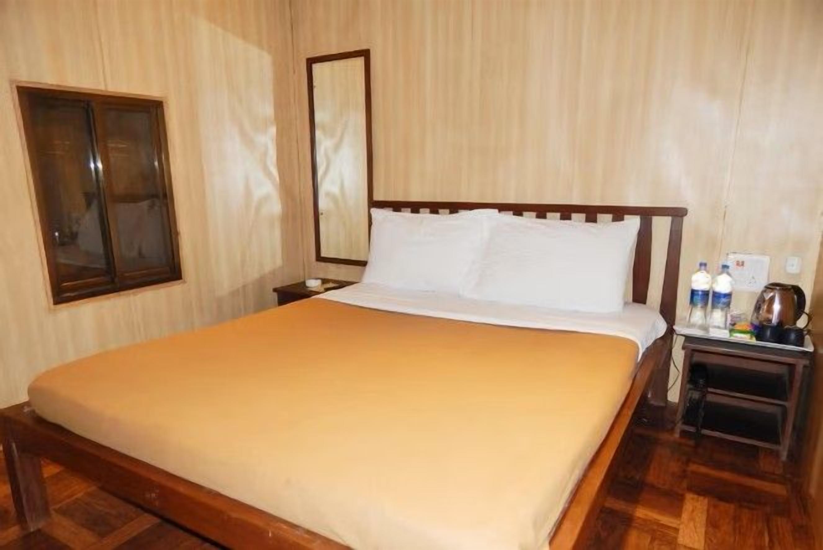 A hotel room with a wooden bed, a nightstand, a mirror, and a window.