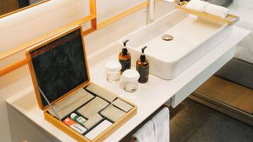 Een badkamer met een witte wastafel, een spiegel, een handdoekhouder en een schaaltje met toiletartikelen.