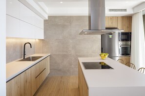 A modern kitchen with a central island, stainless steel appliances, and wooden cabinetry.