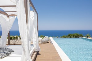 A poolside area with a view of the ocean, a white canopy, and a tiled deck. - Perfect Hideaway for Families & Unmatched Sunsets (Rethymno)
