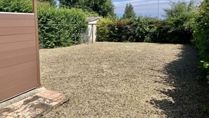 A gravel driveway leading to a small shed surrounded by dense greenery. - Apartment 300m from the beach - Shared outdoor area (Asnelles)