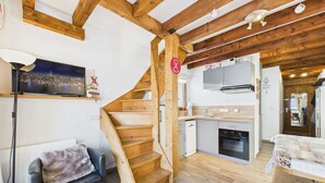 Ein gemütliches Interieur mit einer Holztreppe, einer Küchenzeile und einer Sitzecke mit Sofa und Dekoration.