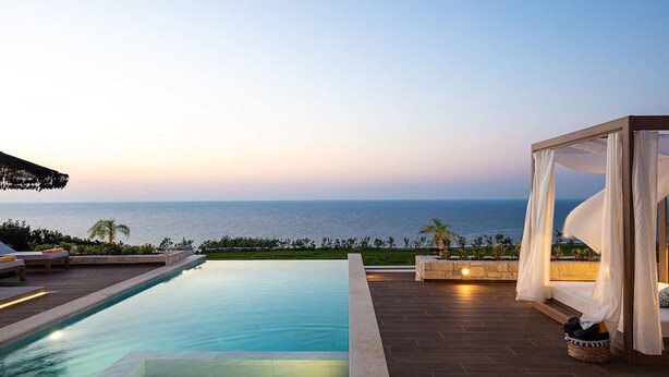 A poolside area with a view of the ocean, a canopy bed, and outdoor seating. - Perfect Hideaway for Families & Unmatched Sunsets (Rethymno)