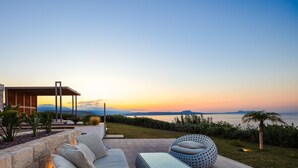 A modern outdoor seating area with a view of the sea at sunset. - Perfect Hideaway for Families & Unmatched Sunsets (Rethymno)
