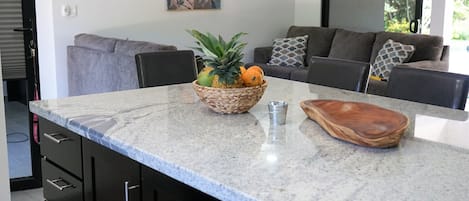 A modern kitchen with dark cabinetry, a granite countertop, and a ceiling fan.