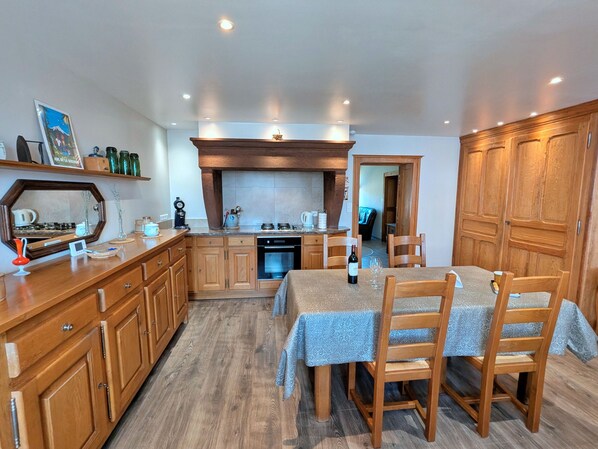 A compact kitchen with wooden cabinets, a dining table with chairs, and a built-in oven.