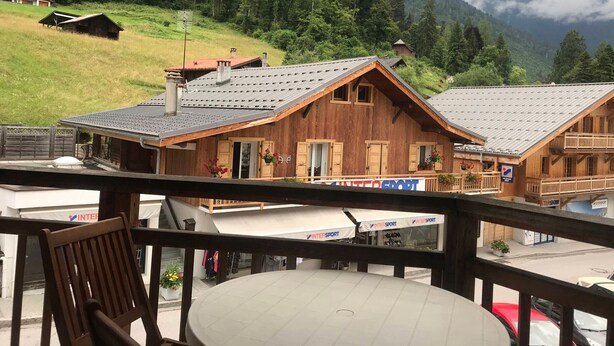 A wooden chalet with a sloped roof, a balcony with a table and chairs, and a view of a mountain range in the background. - Studio for 2 close to Samoëns center (Samoëns)
