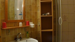 A bathroom with a white sink, a mirror, and a shelf with toiletries. - Studio for 2 close to Samoëns center (Samoëns)